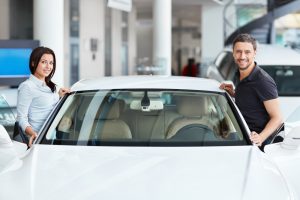 Man and woman getting into car at dealership