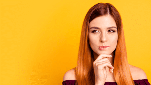 Personal Loans Banner - Young woman looks to the side while thinking against a yellow background