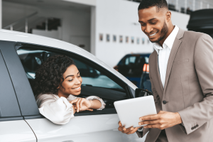 Car Loans Banner - Dealership salesperson showing a tablet to woman in a car