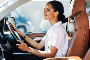 Car Loans Banner - Young woman smiling while sitting at the wheel of a car