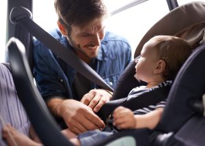 Father safely strapping his child into car seat