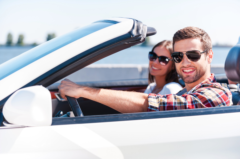 Man and woman travelling in convertible car