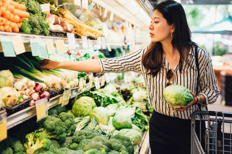 Australian woman choosing green vegetables at the supermarket veggie section