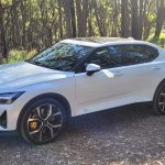 Snow coloured Polestar 2 dual motor EV with performance pack parked in front of forest