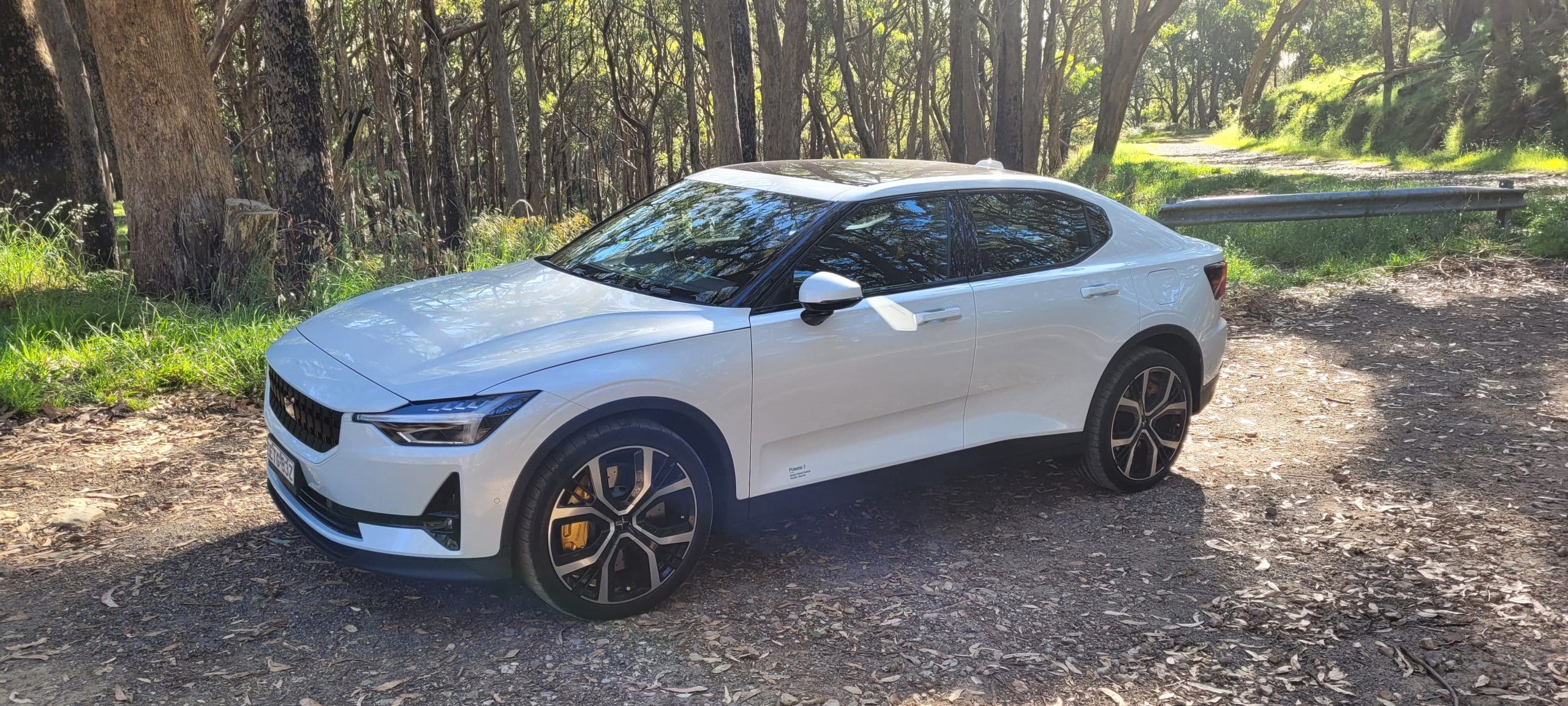 Snow coloured Polestar 2 dual motor EV with performance pack parked in front of forest