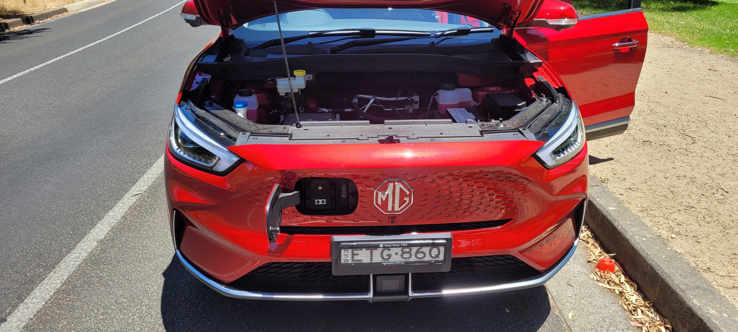 Red MG ZS EV front view with bonnet and charging cover open