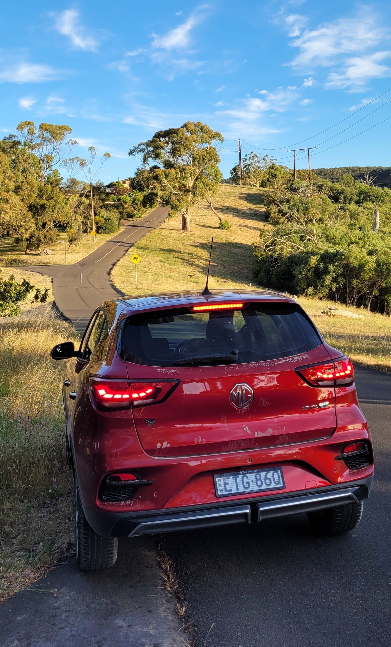 Diamond red metallic MG ZS EV rear view parked on country road in Adelaide hills