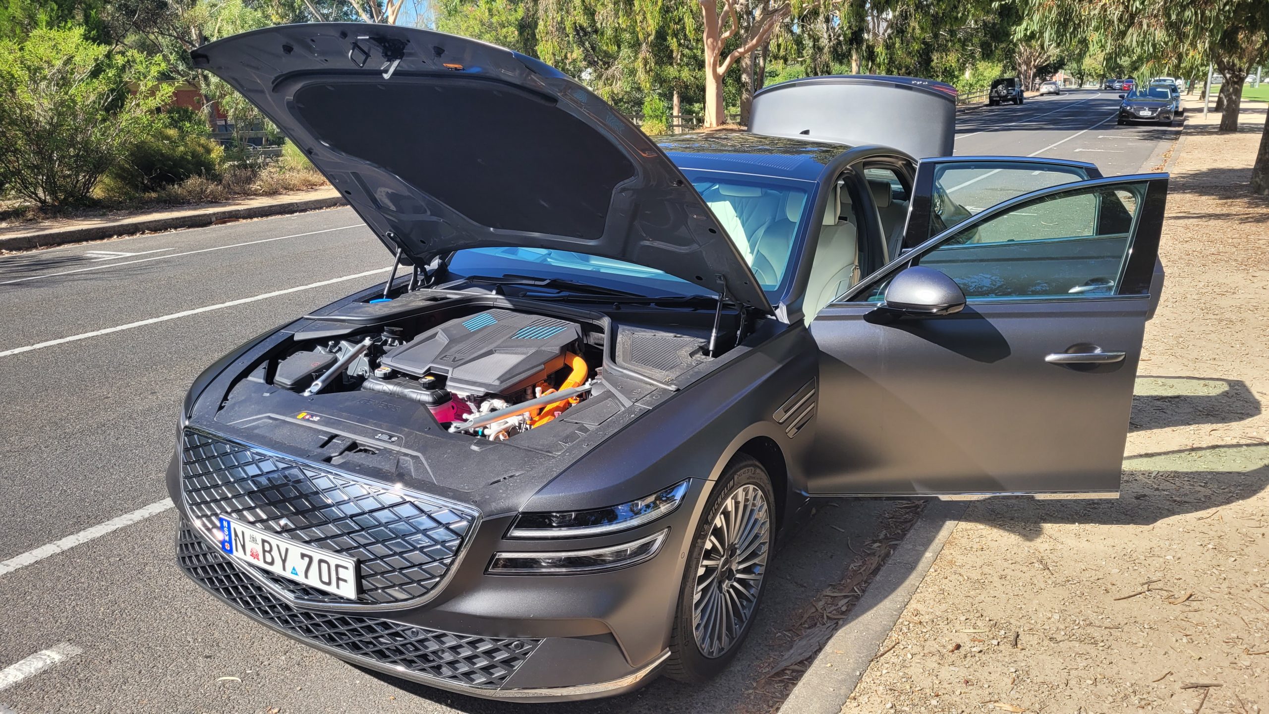Genesis G80 electric vehicle front left view with bonnet open showing electric motor inside