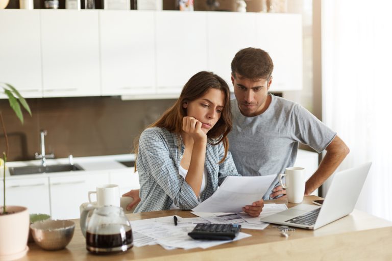 Concerned couple look over their mortgage payment printout in their kitchen