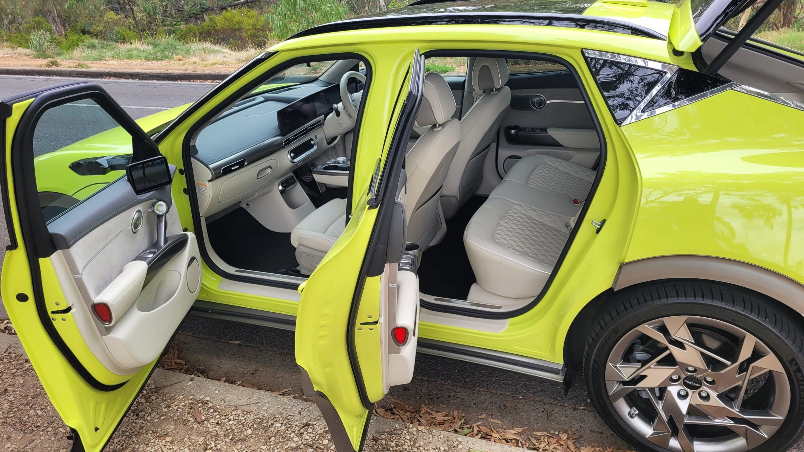 Side view of doors open on the Genesis GV60, looking at the Glacier White interior