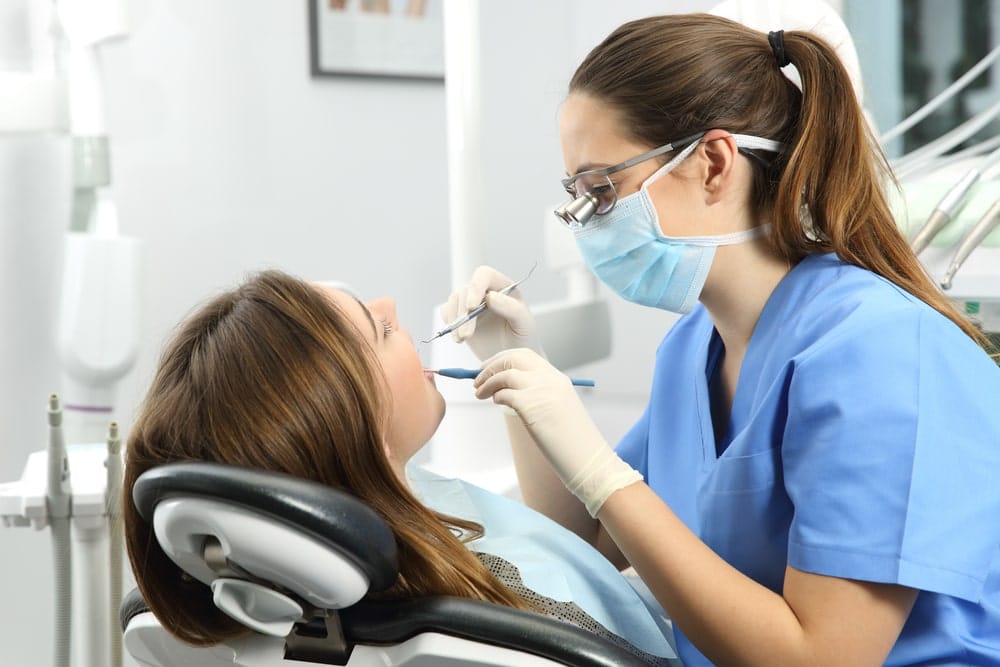 Health Insurance Banner - Woman lying in a dentist's chair having work done in her mouth by a dentist