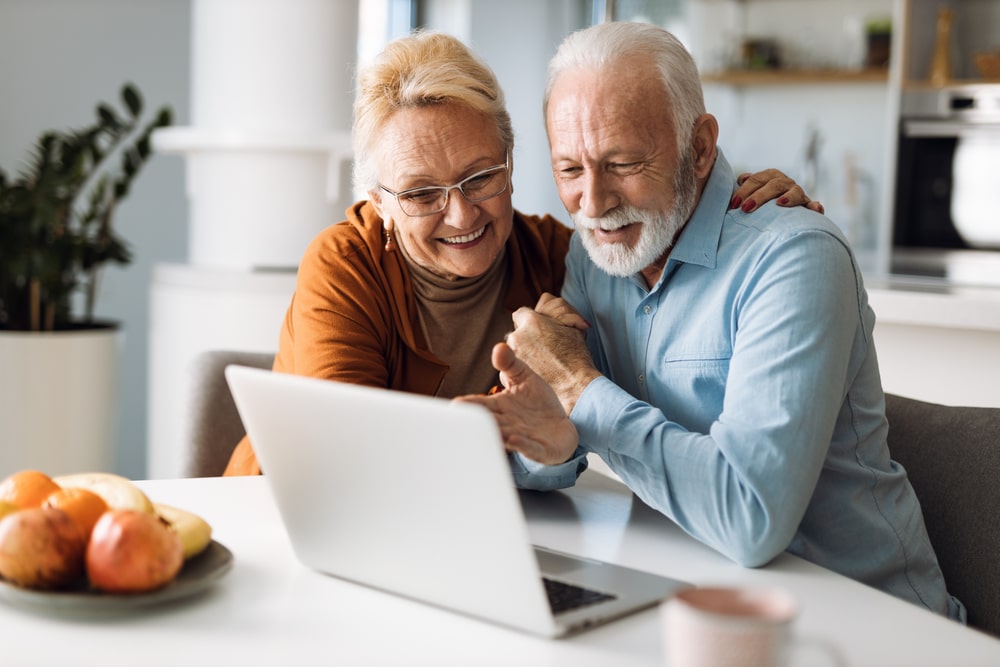 Health Insurance Banner - A senior couple happily looking at their computer.