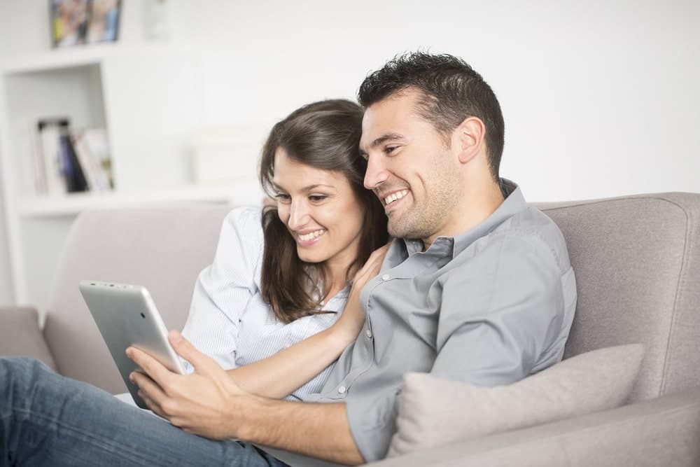 Energy Banner - Couple sitting on the couch looking at the best electricity plans on a tablet