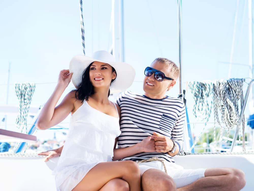 Travel Insurance Banner - Couple smiling and sitting on a boat on a sunny day.
