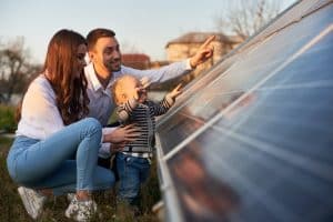 Energy Banner - Couple looking at solar panels up close with their baby child