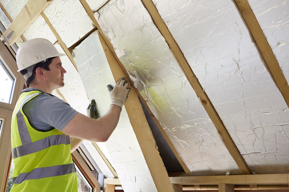 A builder installing an insulating board into the rood of a house.