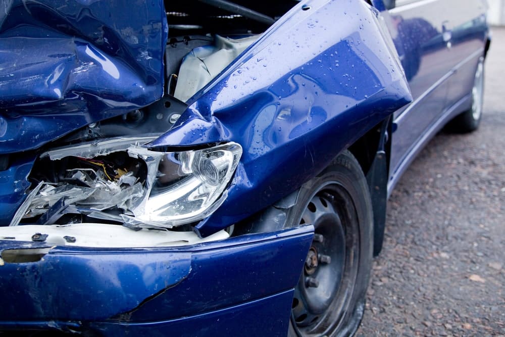 Car Insurance Banner - Front view of a blue car which has been written off in an accident.