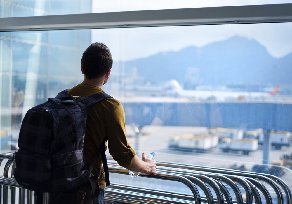 Travel Insurance Banner - Young man waits for his flight at an airport.