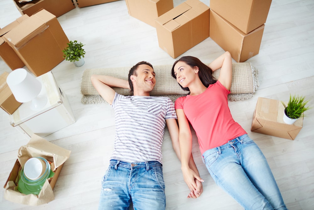Life Insurance Banner - Young couple lying on the ground while moving house surrounded by boxes