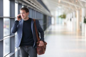 Health Insurance Banner - Expat talking on the phone while at an airport terminal