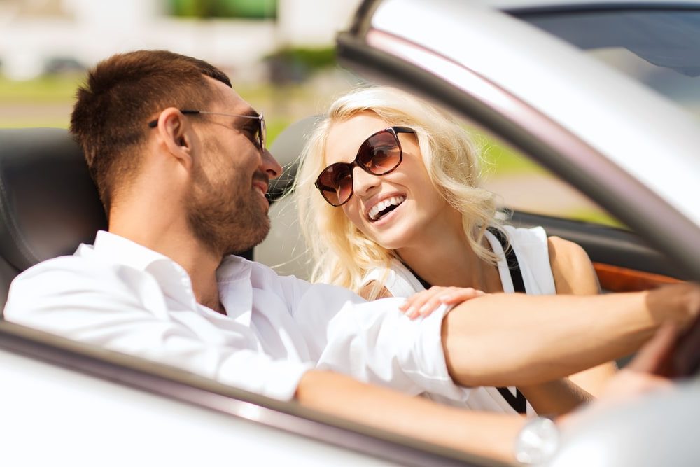 Personal Loans Banner - Young couple smiling at each other while driving in a convertible