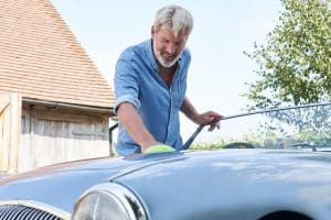 Car Loans Banner - Older man cleans his valuable vintage car