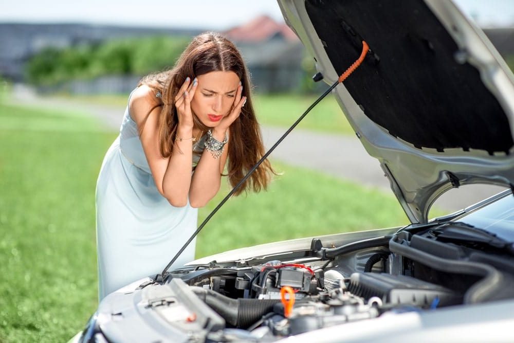 Car Loans Banner - Frustrated woman looking under the bonnet of her car before jump starting the battery
