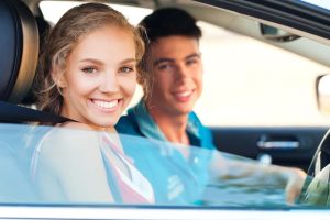 Car Insurance Banner - Young couple smiling while sitting in their car