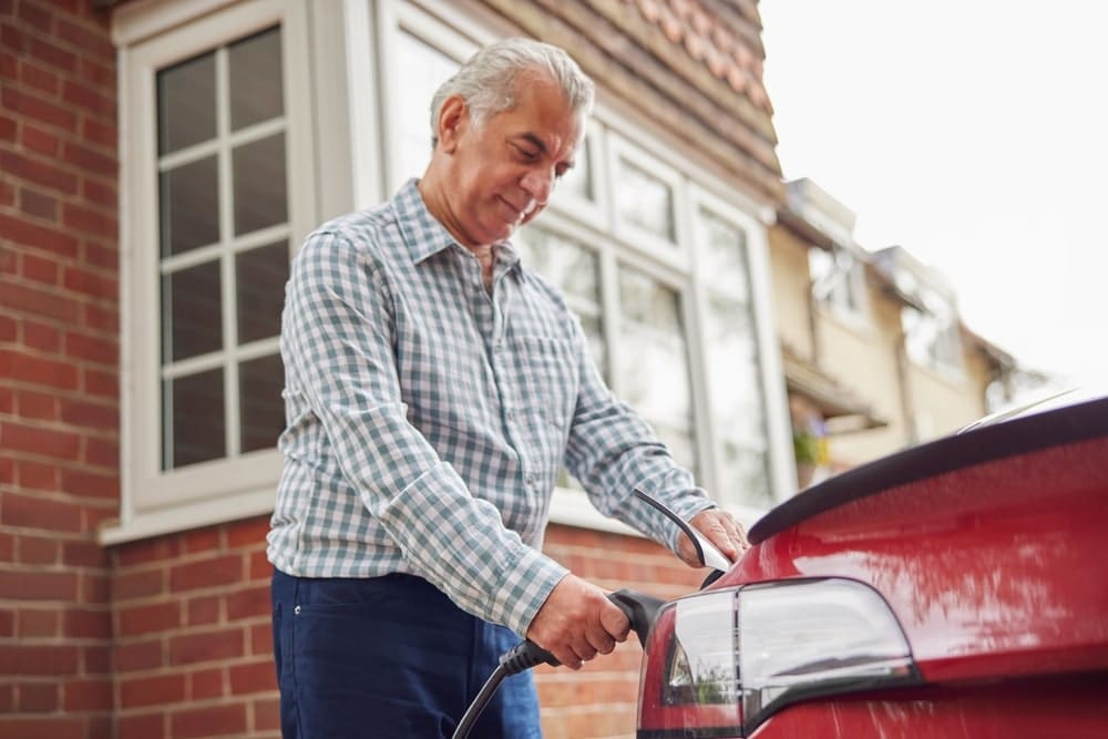 Car Insurance Banner - Senior man charges his hybrid vehicle at home