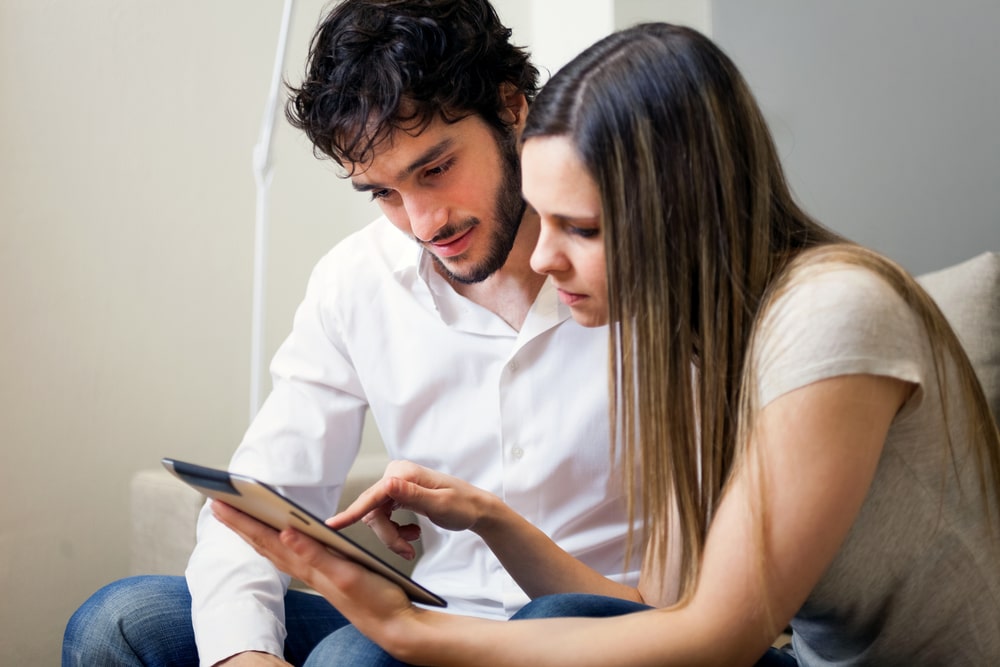 Life Insurance Banner - Young couple looking at life insurance policy riders on a tablet