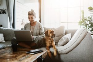 Life Insurance Banner - Woman sitting on the couch on her laptop with her dog