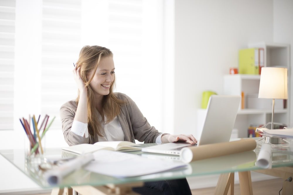 Personal Loans Banner - Young woman smiling at her desk looking at her computer