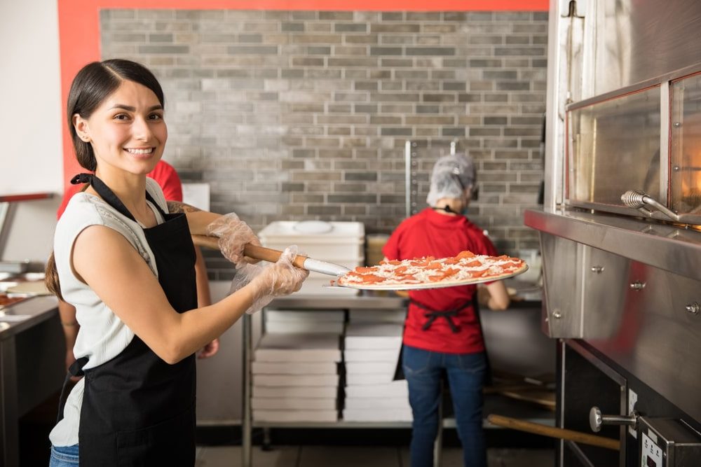 Business Loans Banner - Restaurant worker taking a pizza out of an oven