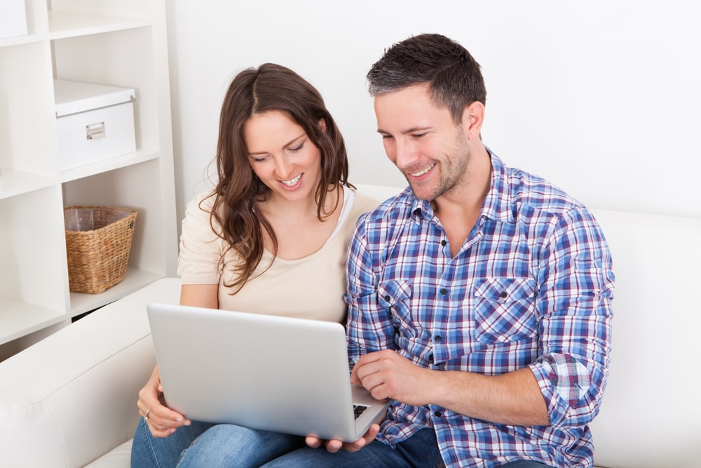 Health Insurance Banner - Couple sitting on the couch together looking at a laptop