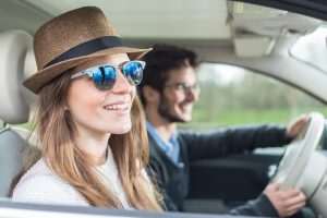 Car Insurance Banner - Young couple smiling while driving through the countryside
