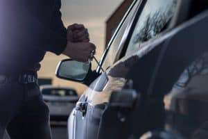 Car Insurance Banner - Man attempting to break into a car and steal it