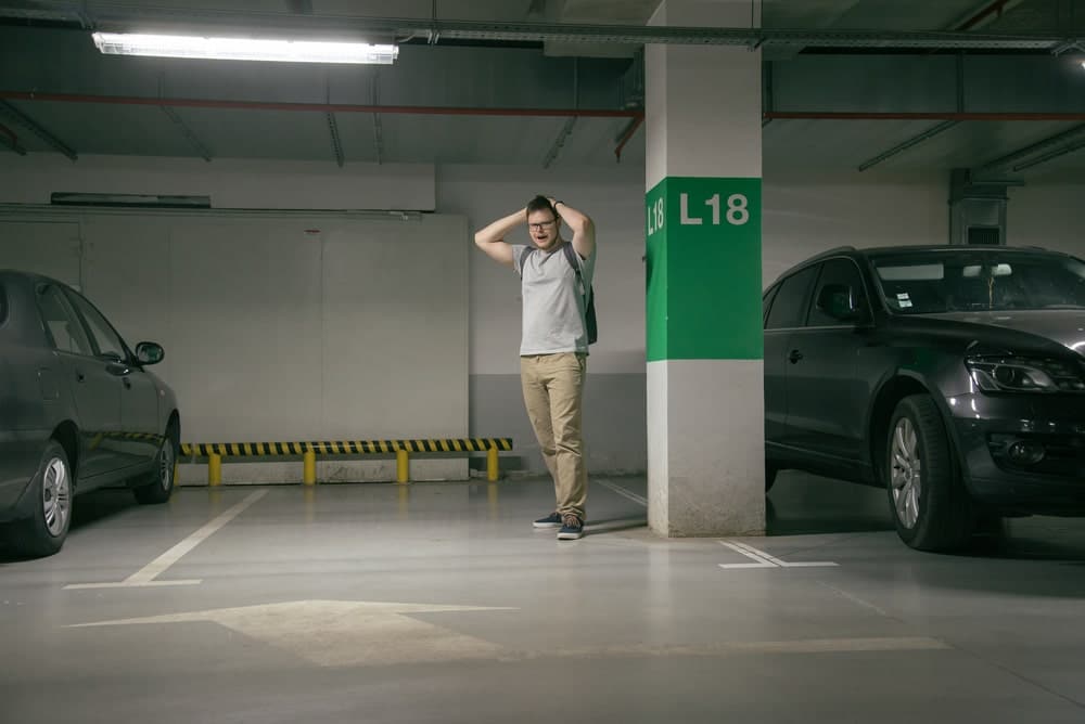 Car Insurance Banner - Young man with hands on his head standing in a carpark after his car is stolen