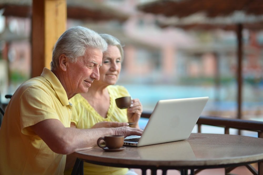 Life Insurance Banner - Senior couple looking at a laptop by the pool