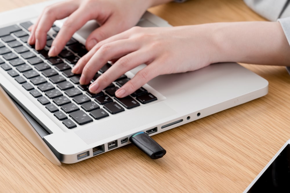 Internet Banner - Woman typing on a laptop with a dongle plugged in