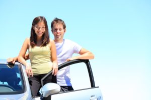 Car Loans Banner - Young couple standing with their new car