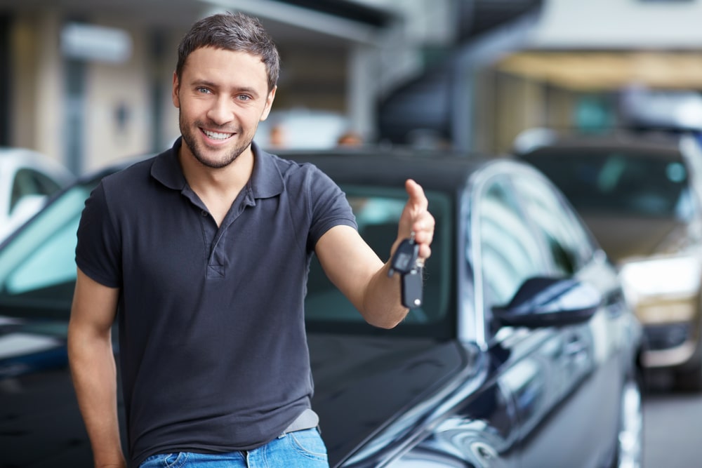 Car Loans Banner - Man smiling holding the keys to his new car
