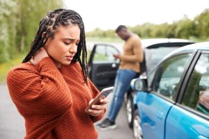 Car Insurance Banner - Concerned woman looking at her phone after having a car accident