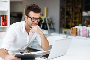 Internet Banner: A man in glasses sitting at a desk with a laptop