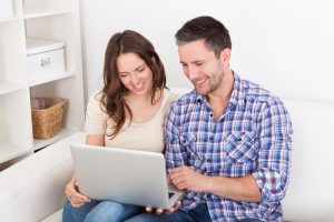 Bank Accounts Banner - Couple comparing bank accounts together on their laptop while sitting on the couch