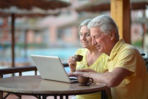 Bank Accounts Banner - Senior couple looking at SMSF bank accounts on their laptop at a resort