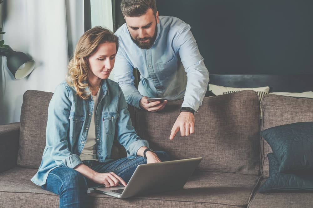 Bank Accounts Banner - Woman sitting on the couch with her laptop while her partner points at the screen