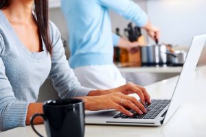 Internet Banner - A woman typing on a laptop in a kitchen