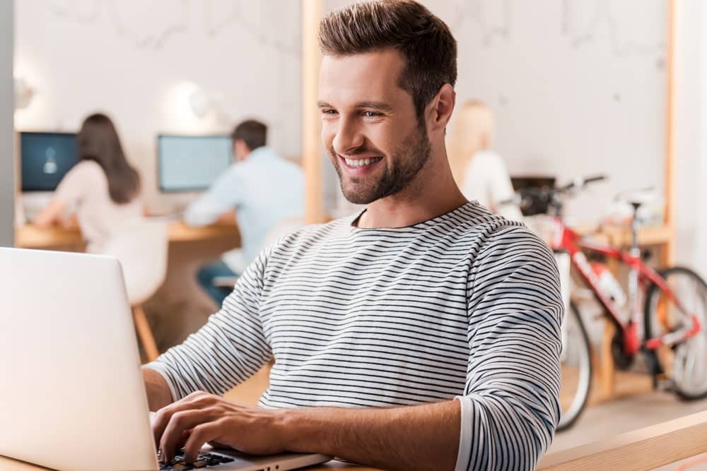 Internet Banner - Man sitting in an office smiling at his laptop