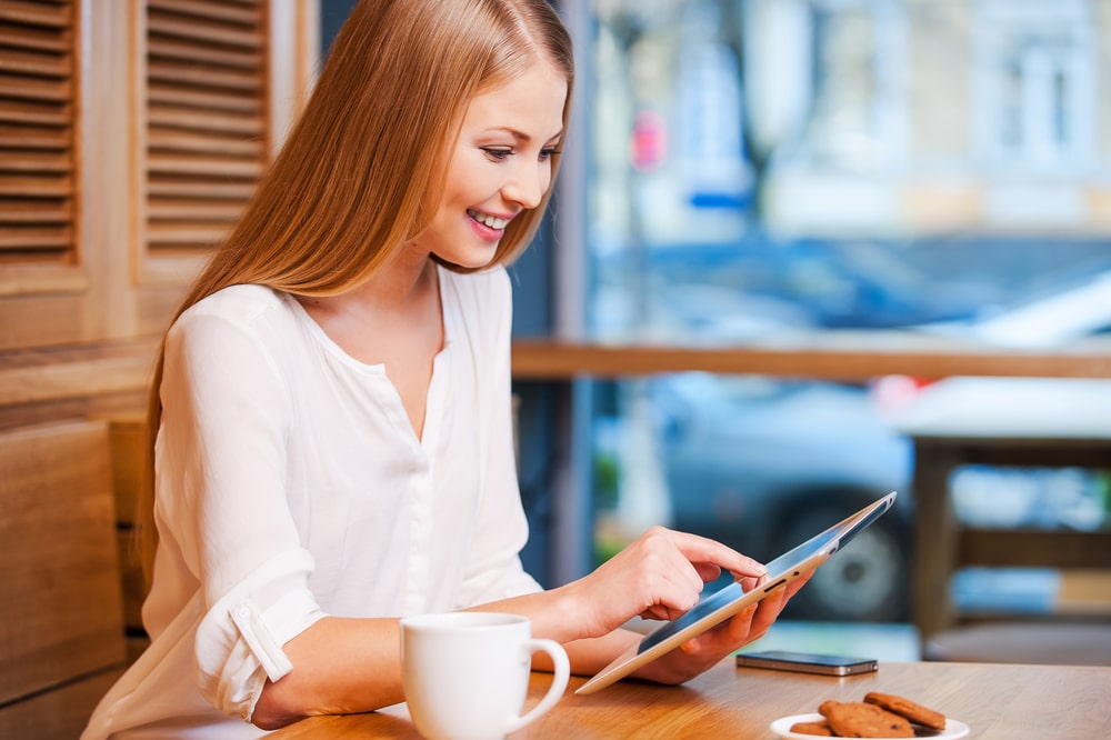 Internet Banner - A young woman using a tablet computer in a cafe