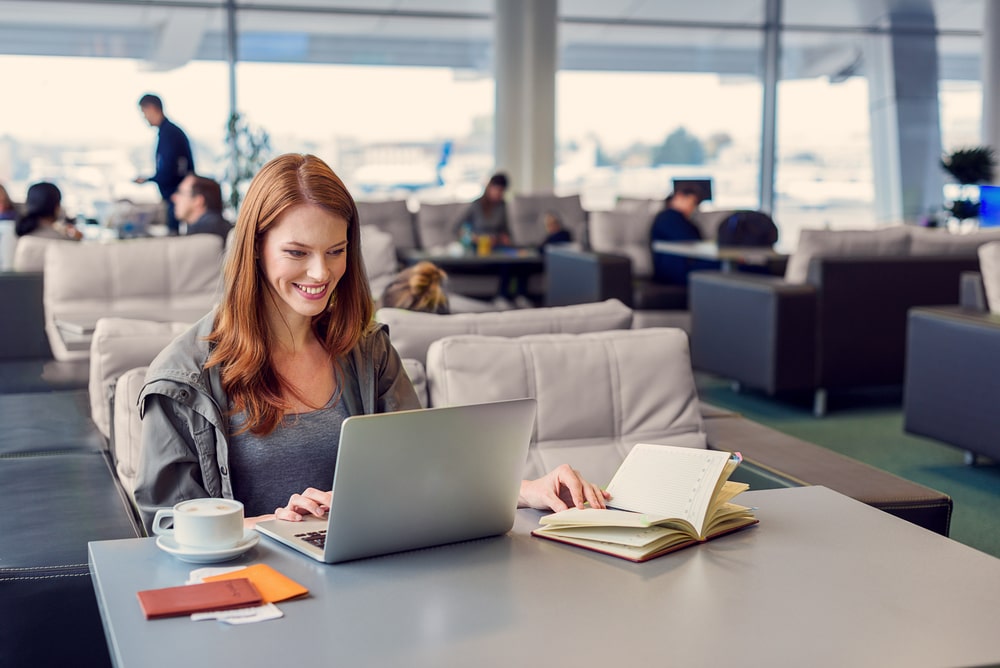 Internet Banner - Woman looking at her laptop on a table in an airport